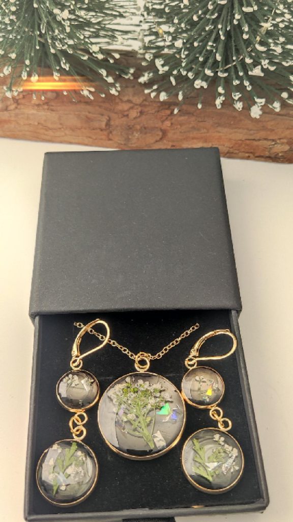 Handmade botanical jewelry set by Vaina featuring real white dried flowers in resin with gold-plated stainless steel frames, displayed in a luxury black gift box.